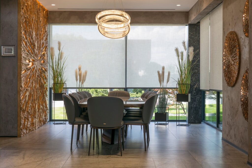 Roller blinds in the interior. Automatic solar shades large size on the windows. Modern interior with wood decor panels on walls. Plants in hi-tech flower pots. Electric sunscreen curtains for home.